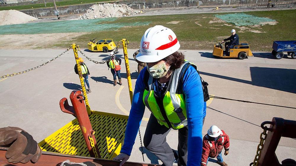 woman in hard hat climbing on to a utility truck